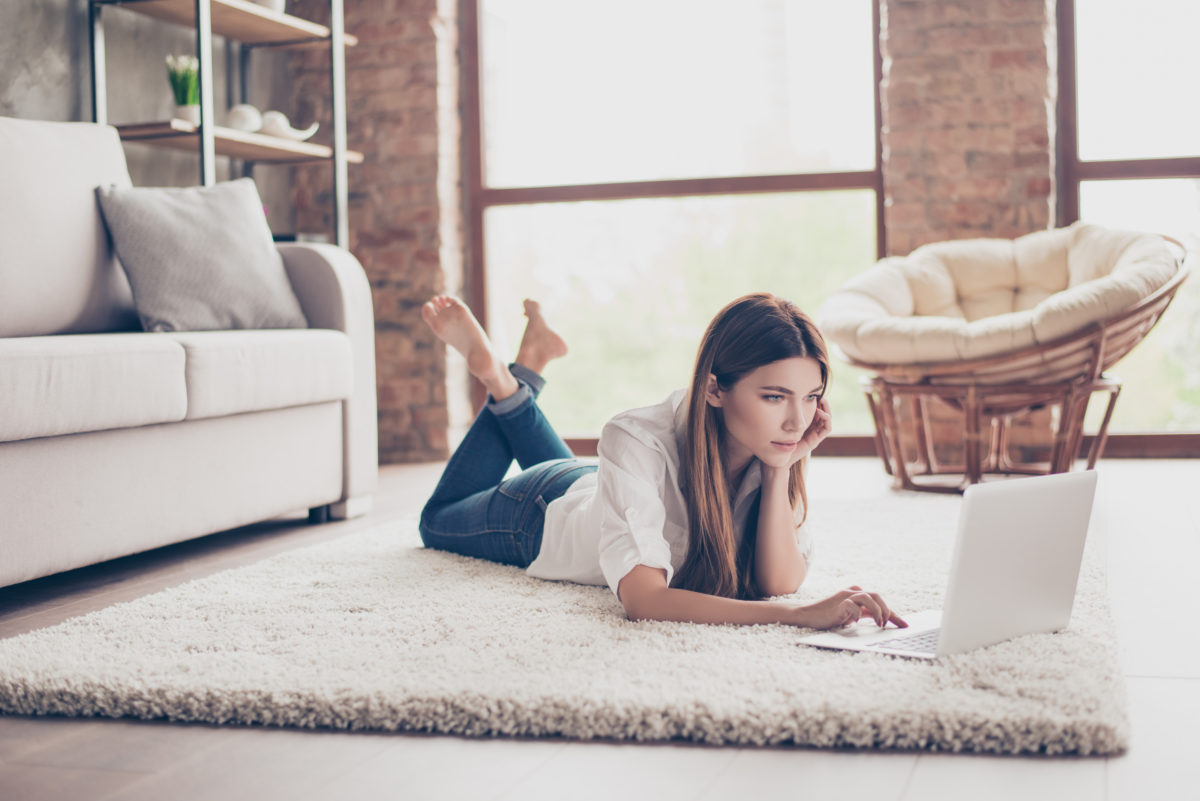 A young woman browses the internet on her living room floor